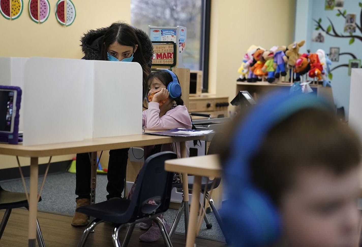 Andrea Friederichs, a teacher's aide, helped a student in a group of mostly kindergarten students do her distance learning lesson at Tierra Encantada in Minneapolis.