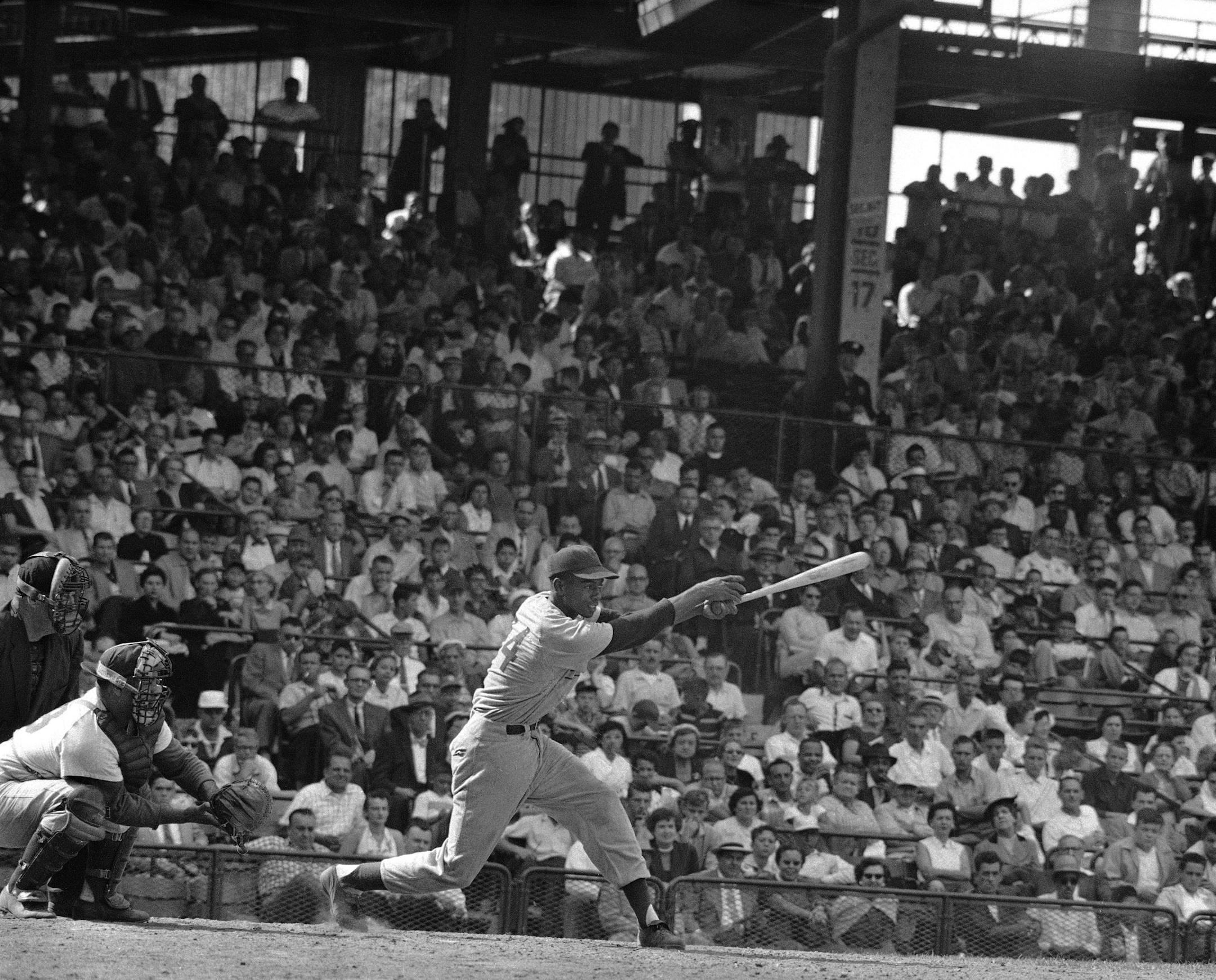 FILE - In this Aug. 31, 1955, file photo, Chicago Cubs' Ernie Banks, center, demonstrates the long stride and wrist action which has brought him close to the leaders in the National League home run race at Ebbets Field in New York. The Cubs announced Friday night, Jan. 23, 2015, that Banks had died. The team did not provide any further details. Banks was 83. (AP Photo/File)