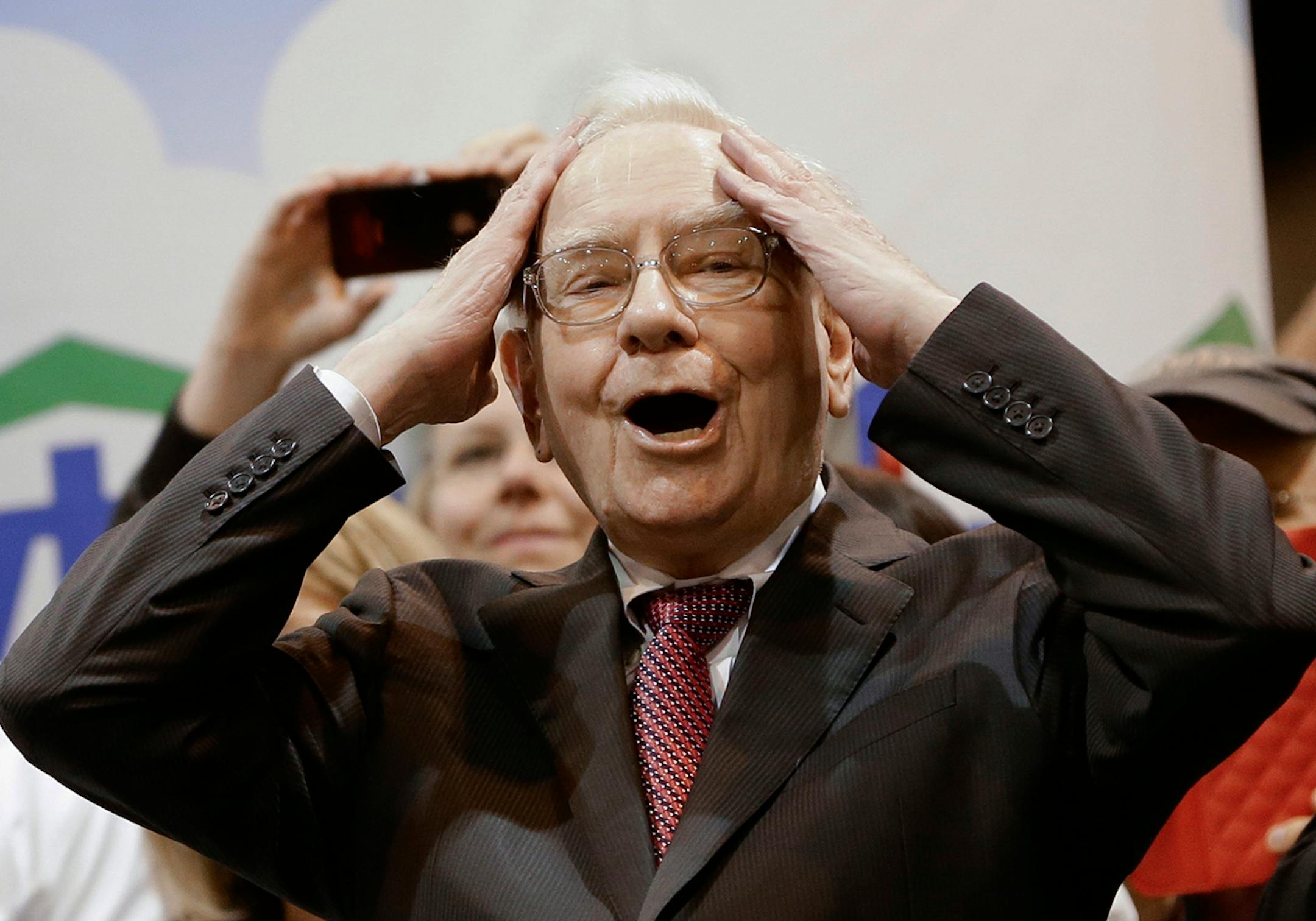 Berkshire Hathaway Chairman and CEO Warren Buffett reacts at the newspaper throwing competition while touring the exhibition floor prior to the annual shareholders meeting on Saturday, May 3, 2014, in Omaha, Neb. More than 30,000 shareholders are expected to fill the CenturyLink Arena to hear Buffett and Berkshire Vice Chairman Charlie Munger discuss their business. (AP Photo/Nati Harnik)