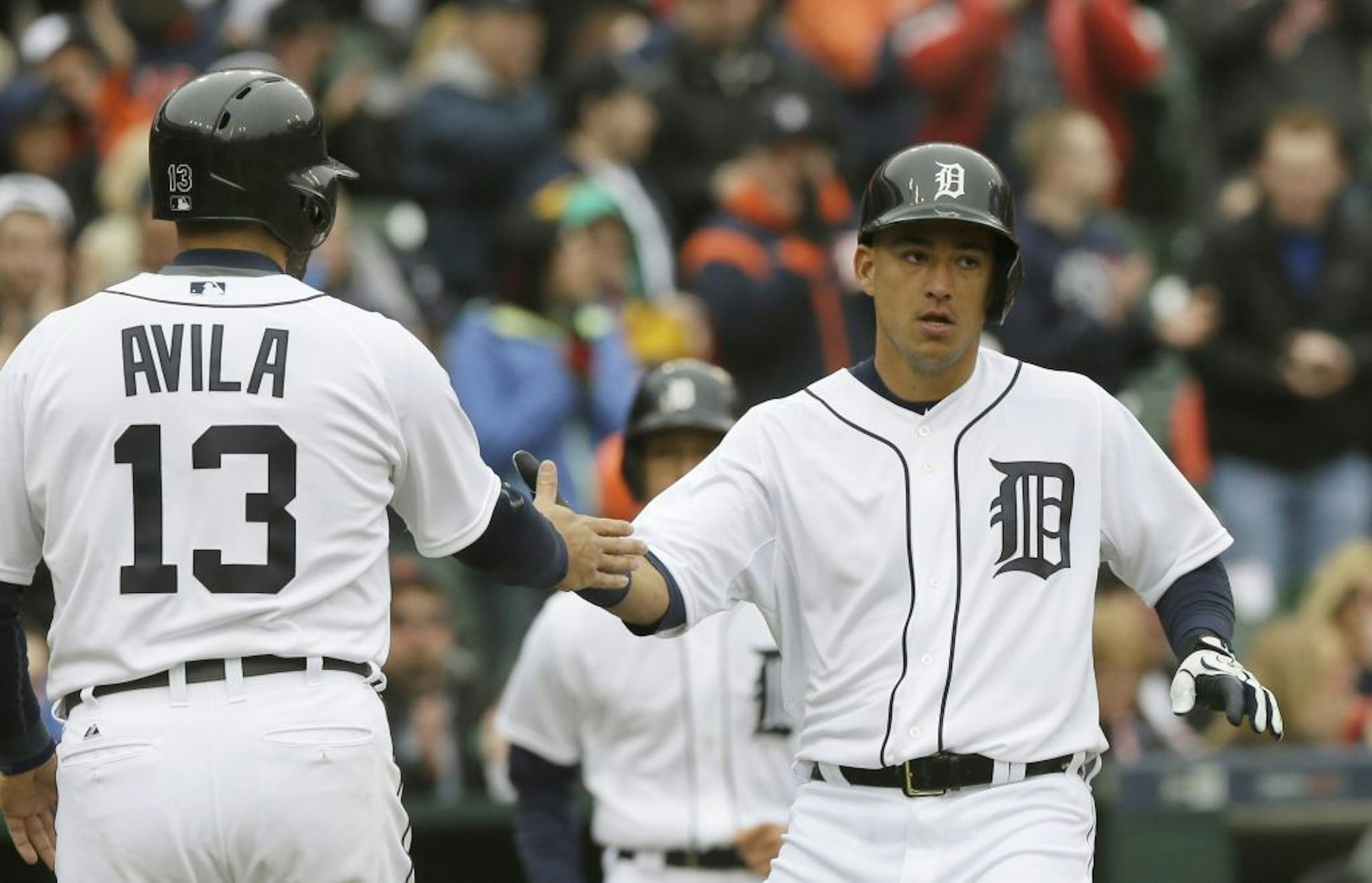 Detroit Tigers' Alex Avila (13) and Jose Iglesias score on a single by Ian Kinsler during the third inning of a baseball game against the Minnesota Twins, Wednesday, April 8, 2015, in Detroit.