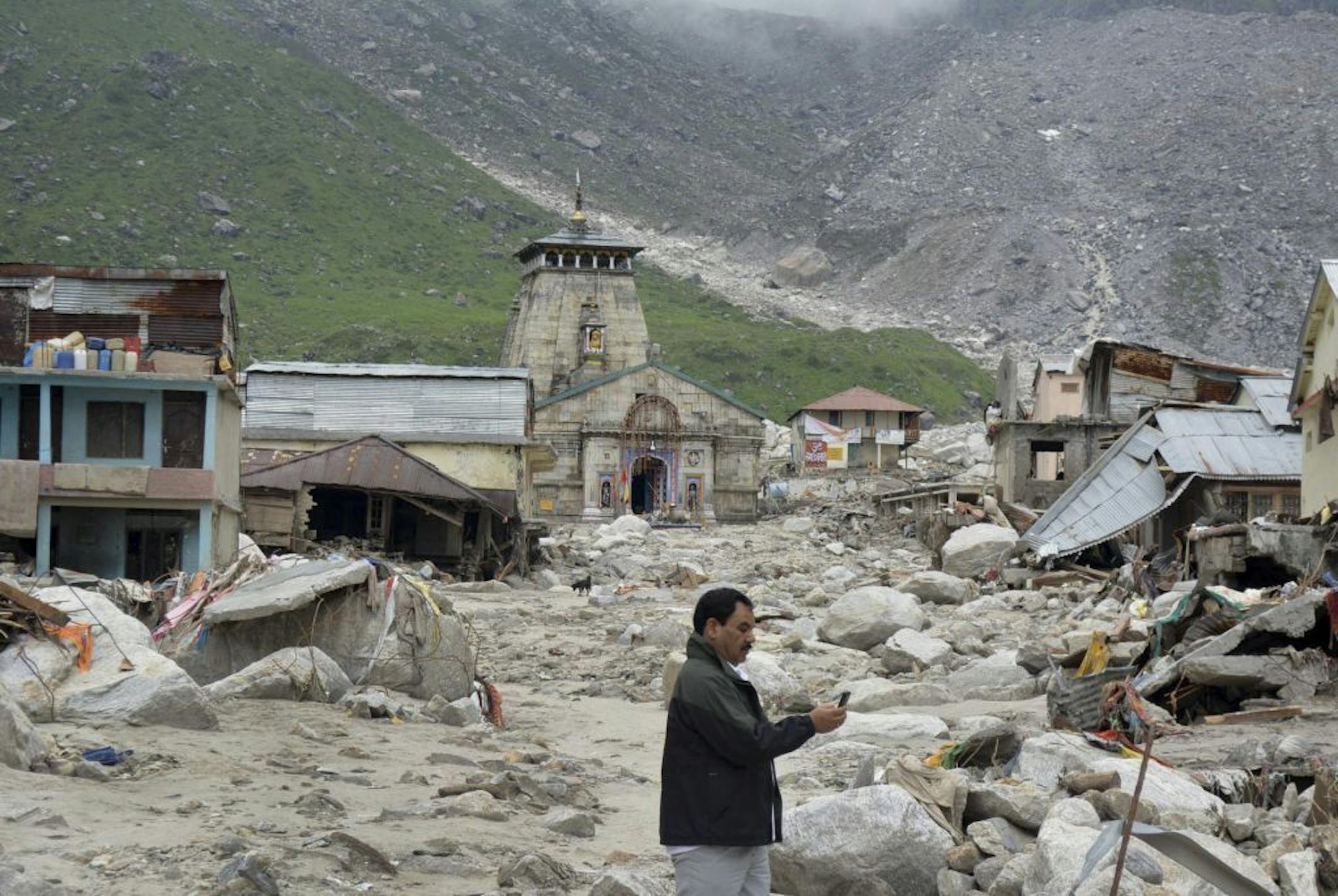 In this Thursday June 20, 2013, photo, a pilgrim takes pictures of an area devastated following heavy monsoon rains at Kedarnath, in the northern Indian state of Uttrakhand.