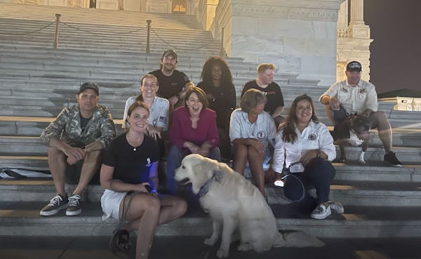 U.S. Sen. Amy Klobuchar on the U.S. Capitol steps with Amanda Barbosa, whose husband, former Army helicopter pilot Rafael Barbosa, was diagnosed with 