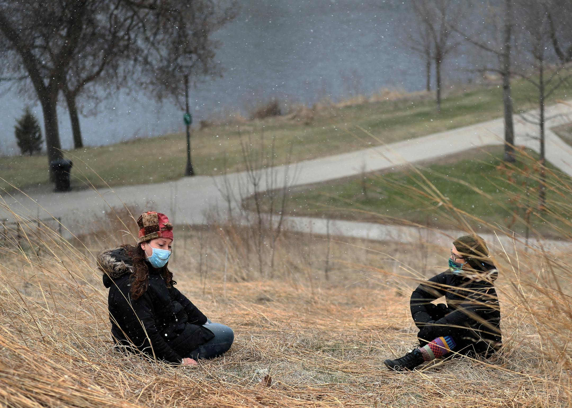 Powderhorn neighborhood neighbors and friends Spirit Angelfish, left, and Asher Edes, sat in the tall grass while social distancing in Powderhorn Park and talked Thursday, April 9, 2020, in Minneapolis, MN. They were catching up, commiserating over the Coronavirus outbreak and lamenting closed gathering spots in the Midtown Global Market. Angelfish said 2020 had been a rough year economically for her as a gig economy worker up to the Coronavirus outbreak but that the pandemic had made things eve