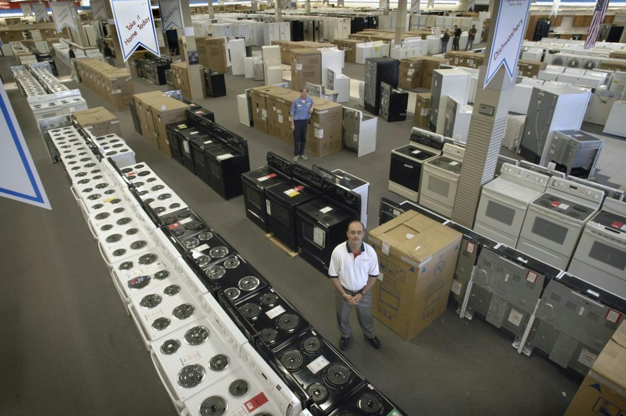 Apple Valley store manager Jim Callahan (foreground) stands on the huge sales floor among the ranges. The store has appliances of all kinds, ready to buy right off the sales floor. GENERAL INFORMATION: APPLE VALLEY, MN. 3/19/2003: This is a business story, to be used as a centerpiece, on a thriving local business, ApplianceSmart Factory Outlet, a business that takes appliance closeouts, factory overruns and discount models and sells them at discount prices. It has three other outlets in the Twin