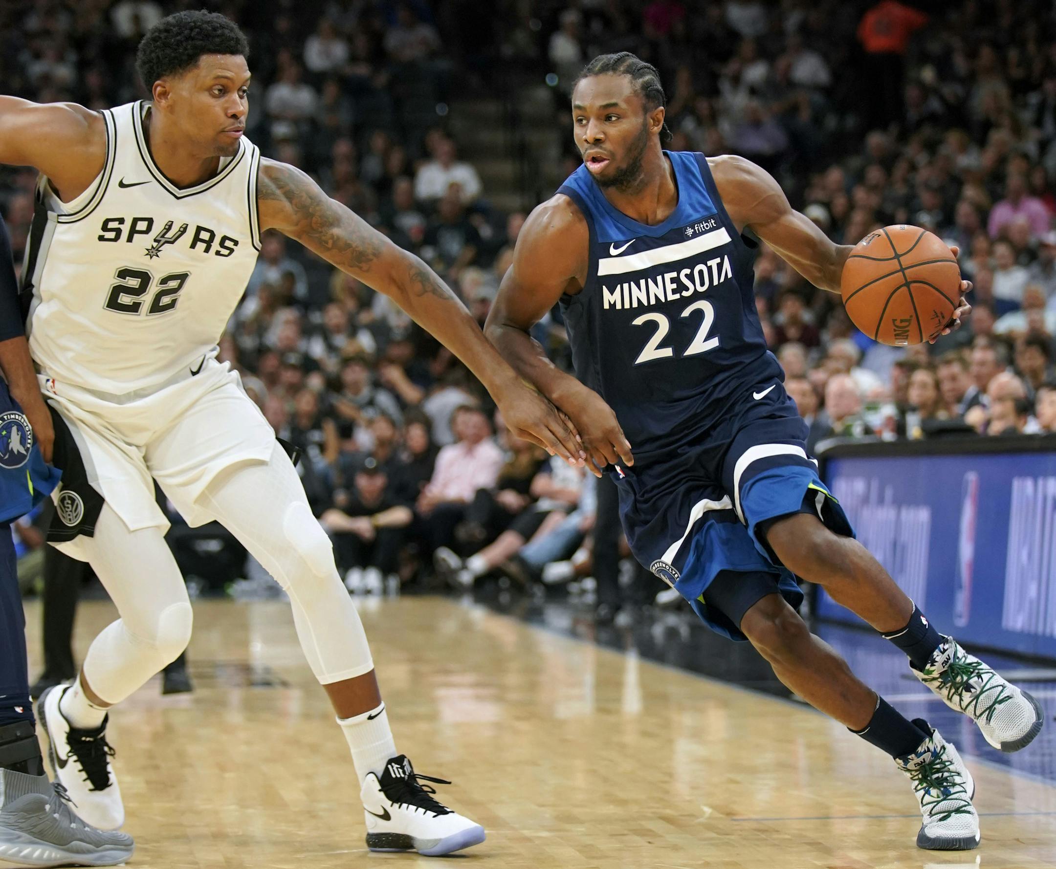 Minnesota Timberwolves' Andrew Wiggins, right, drives around San Antonio Spurs' Rudy Gay during the first half of an NBA basketball game, Wednesday, Oct. 18, 2017, in San Antonio. (AP Photo/Darren Abate)