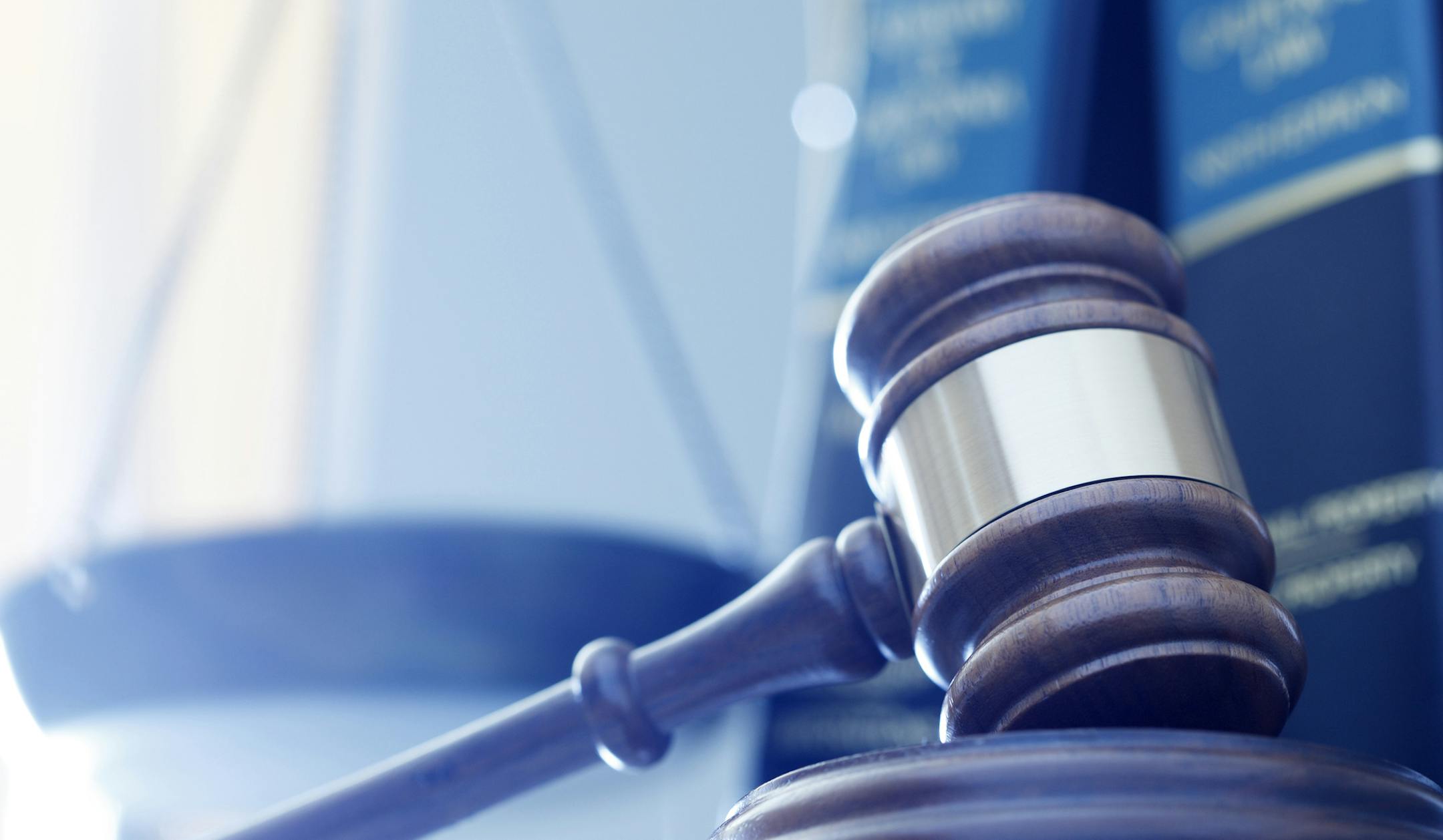 iStock
A gavel rests on its sounding block with a several law books and a justice scale out of focus in the background.