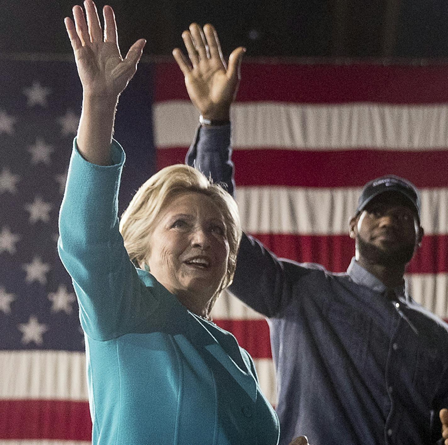 Democratic presidential candidate Hillary Clinton, left, accompanied by LeBron James, right, takes the stage at a rally at the Cleveland Public Auditorium in Cleveland, Sunday, Nov. 6, 2016. (AP Photo/Andrew Harnik) ORG XMIT: MIN2016110616262227