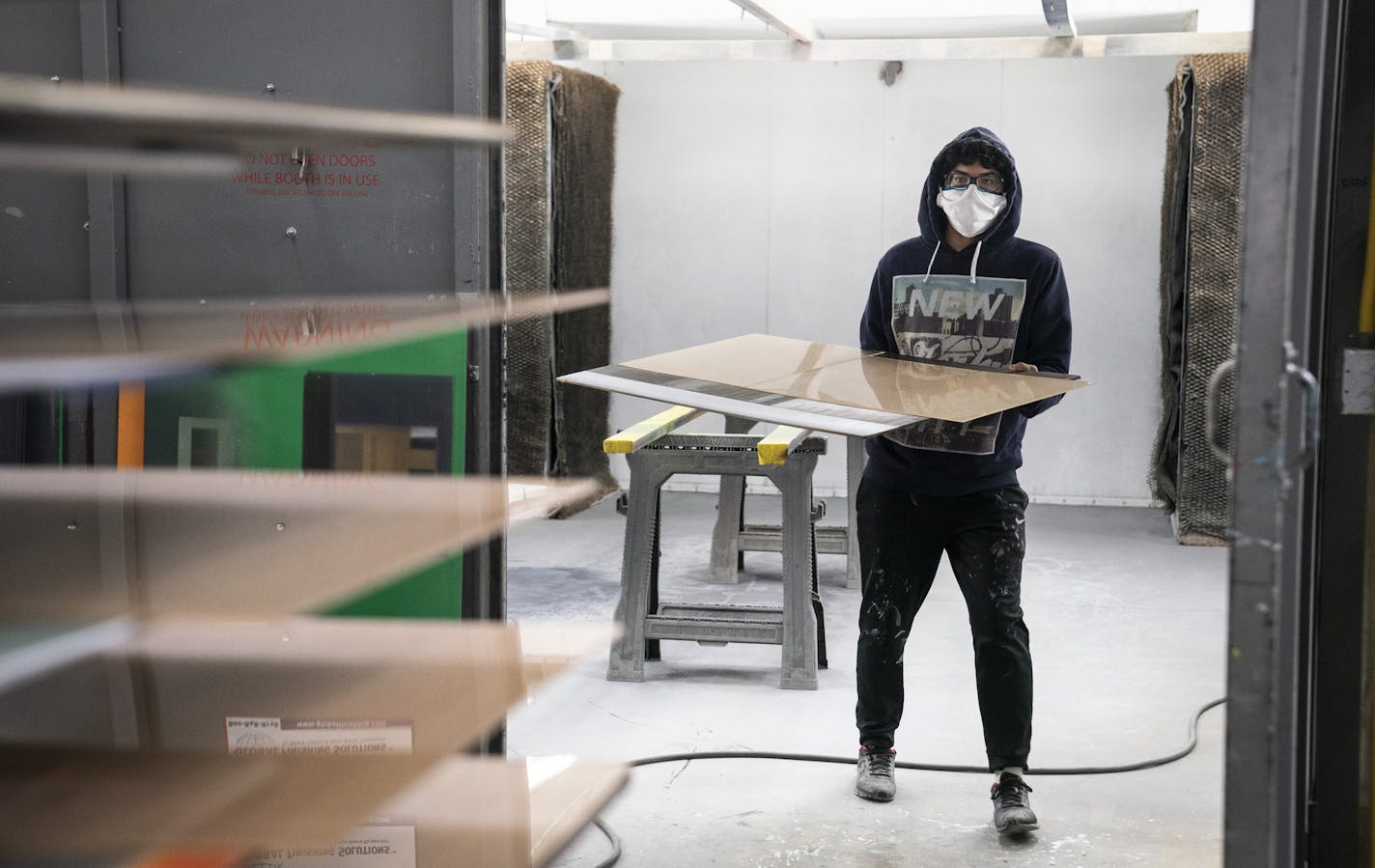 Eward Ajuirre sanded in the spray booth while wearing a mask on the production floor at Indigo Signworks in Chanhassen, Minn., on Thursday, April 16, 2020. ] RENEE JONES SCHNEIDER &#xa5; renee.jones@startribune.com Chanhassen-based Indigo Signworks brought its Minnesota workers back on Monday and the first week has been weird. Blue tape around the printer and desks to mark 6-ft. and some different ways of doing business.