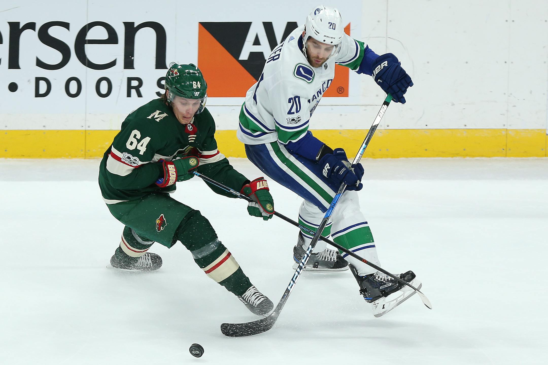 Minnesota Wild's Mikael Granlund (64) and Vancouver Canucks' Brandon Sutter (20) go after the puck in the third period