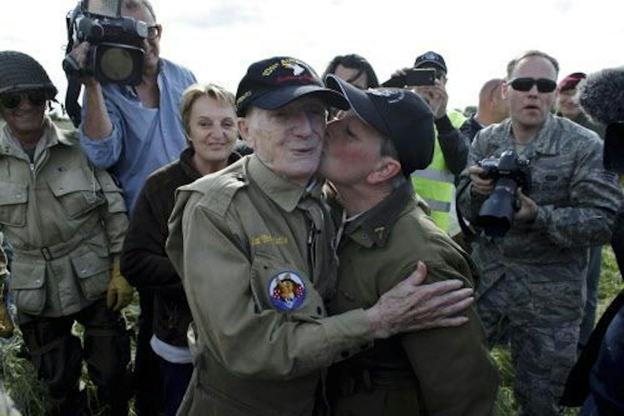93 year old U.S WW II veteran Jim Martin of the 101st Airborne, is kissed by an unidentified woman after he completed a tandem parachute jump onto Utah Beach, western France, Thursday June 5, 2014.