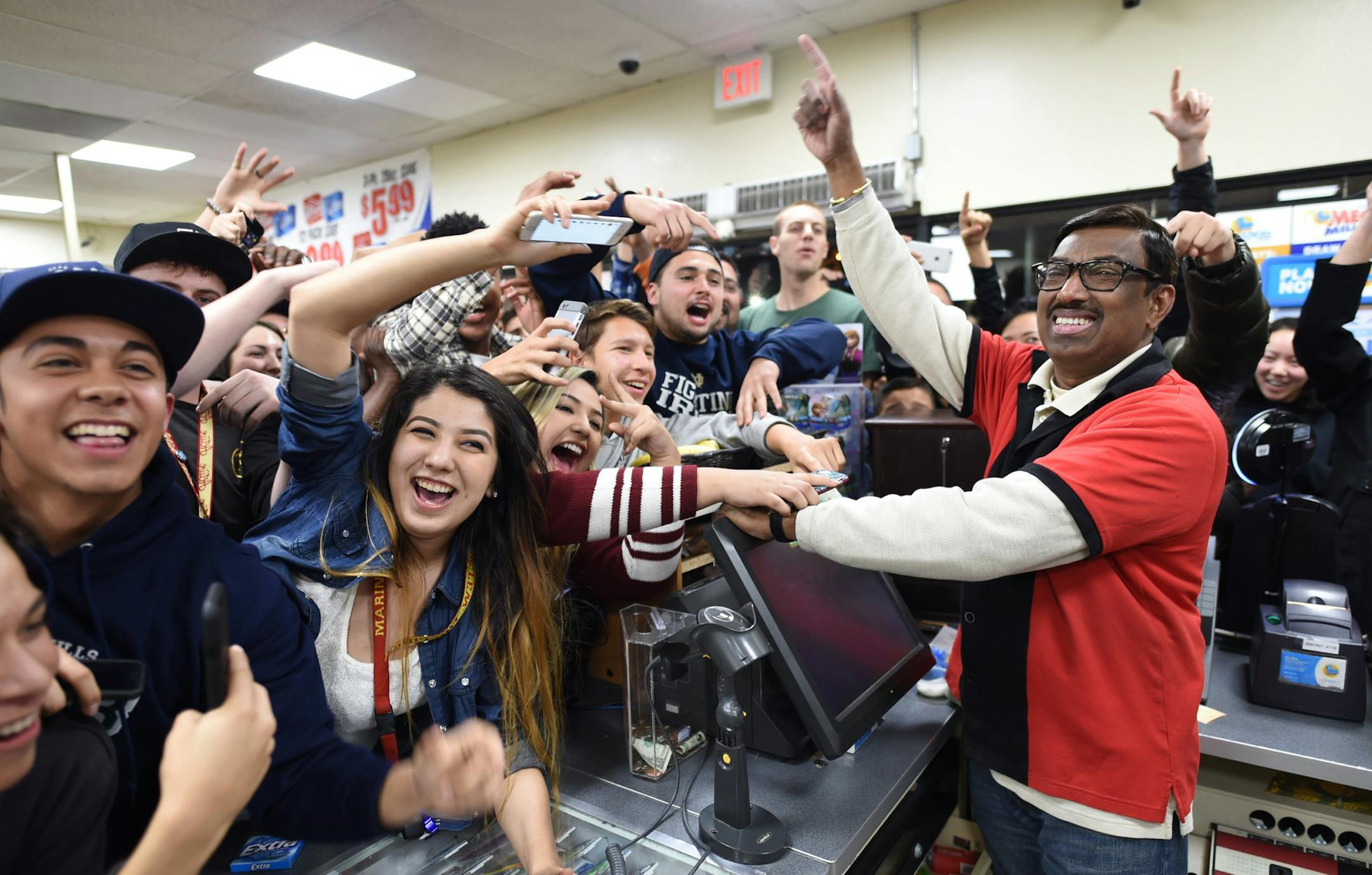 7-Eleven store clerk M. Faroqui celebrates with customers after learning the store sold a winning Powerball ticket on Wednesday, Jan. 13, 2016 in Chino Hills, Calif.