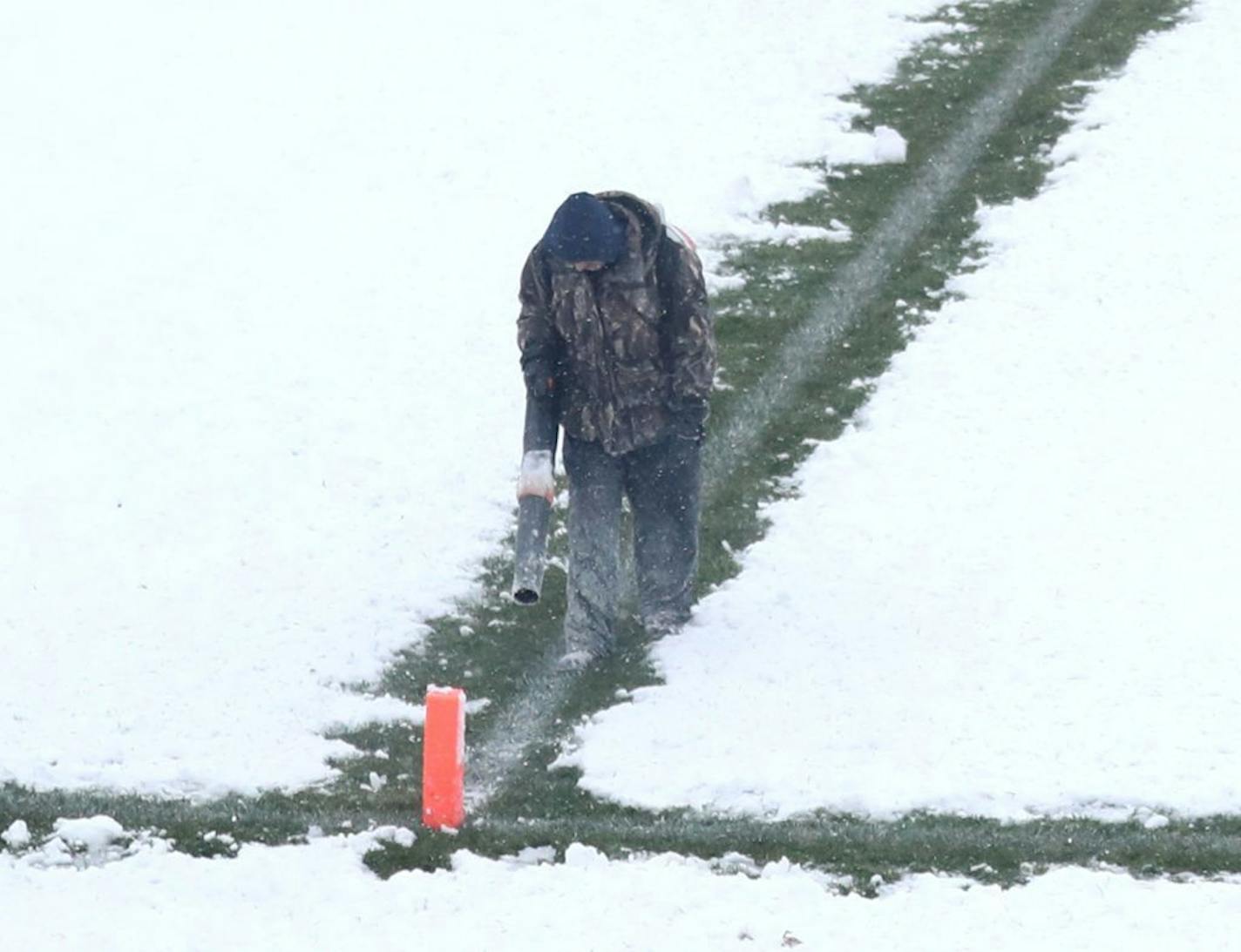 A worker used a power blower to move snow from the field at Blaine High School on Friday before the football game between Armstrong and Blaine.