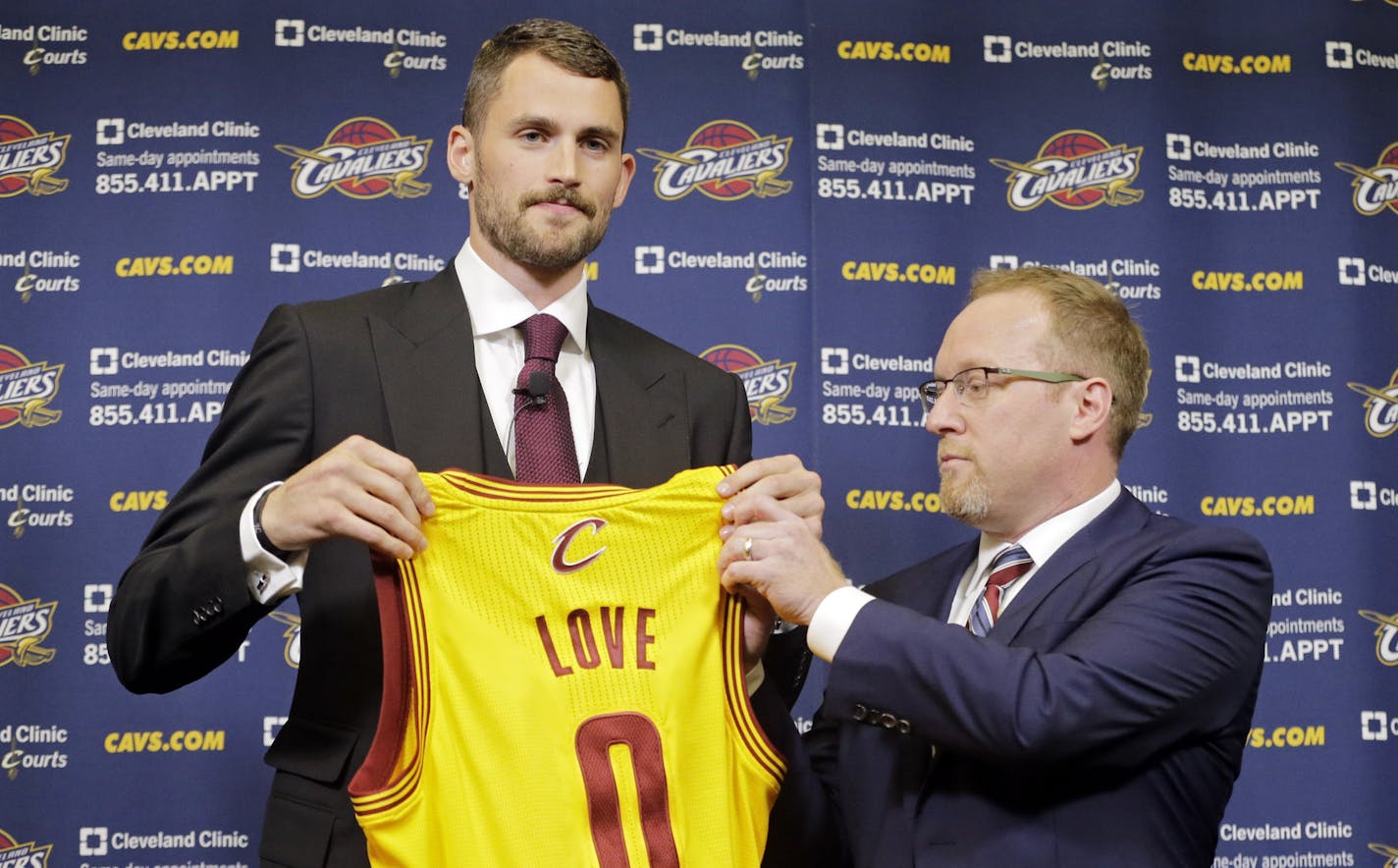 Cleveland Cavaliers' Kevin Love holds up his new jersey with general manager David Griffin at the NBA basketball team's practice facility in Independence, Ohio Tuesday, Aug. 26, 2014. Love was acquired from the Minnesota Timberwolves in a three-team trade that was finalized over the weekend. (AP Photo/Mark Duncan)