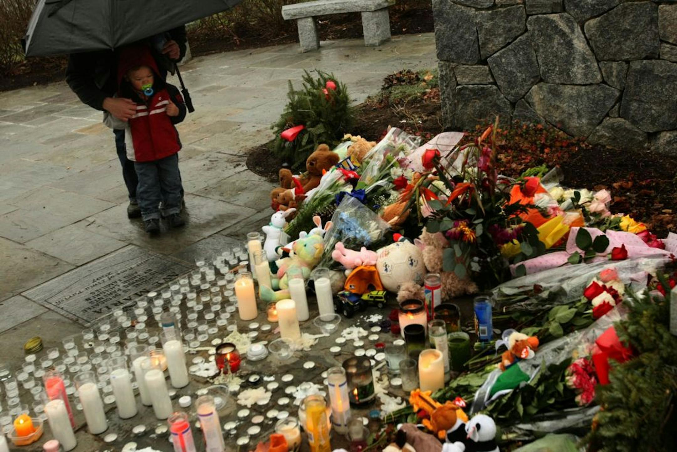 A mother and son spend time at a memorial left at the Shrine of the Virgin Mary for victims of the Sandy Hook Elementary School shooting in Newtown, Connecticut on Sunday, December 16, 2012.