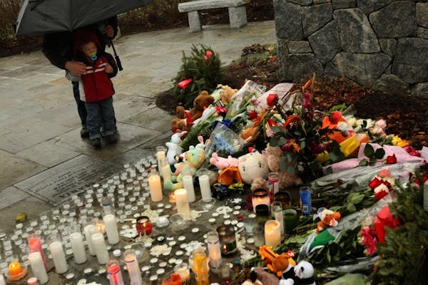 A mother and son spend time at a memorial left at the Shrine of the Virgin Mary for victims of the Sandy Hook Elementary School shooting in Newtown, C