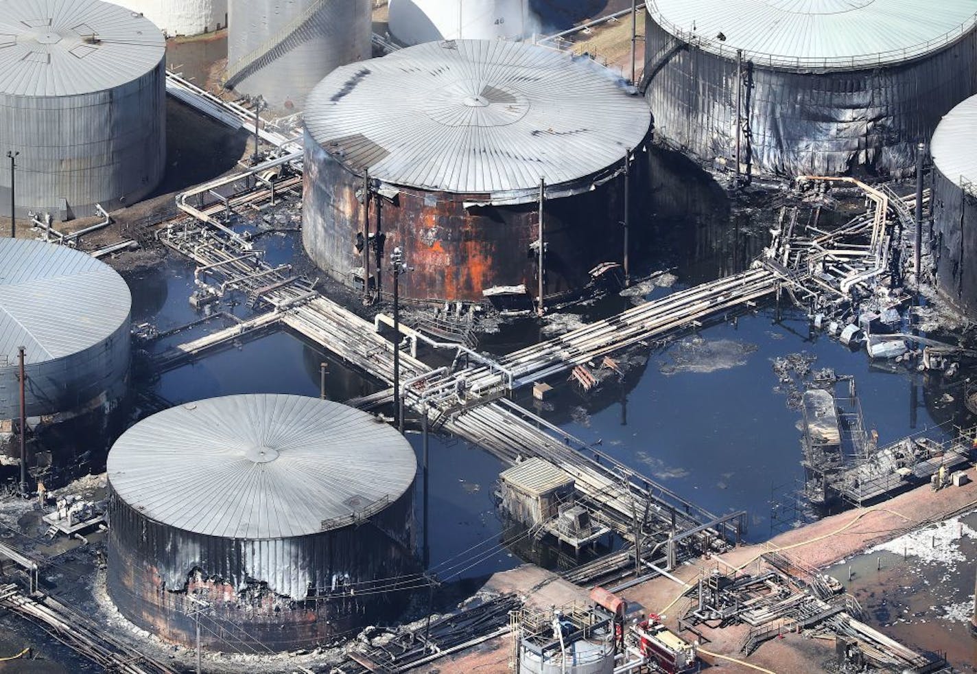 In this aerial photo of Husky Energy oil refinery taken Saturday morning damaged storage tanks, mangled pipes and pond of water and other liquids are visible. There are still hot spots as evidenced by small amounts of smoke rising from the top at top center.