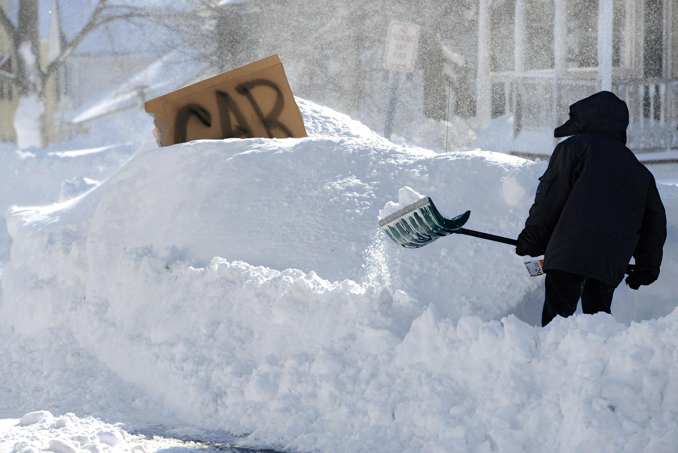 A boy digs around a car marked with a sign on a street in Windsor Locks, Conn., Saturday, Feb. 9, 2013. A behemoth storm packing hurricane-force wind gusts and blizzard conditions swept through the Northeast overnight.