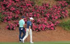 Gary Woodland and Dustin Johnson walk past some of the few blooming azaleas on their way to the 12th green during their practice round for the Masters