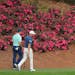 Gary Woodland and Dustin Johnson walk past some of the few blooming azaleas on their way to the 12th green during their practice round for the Masters