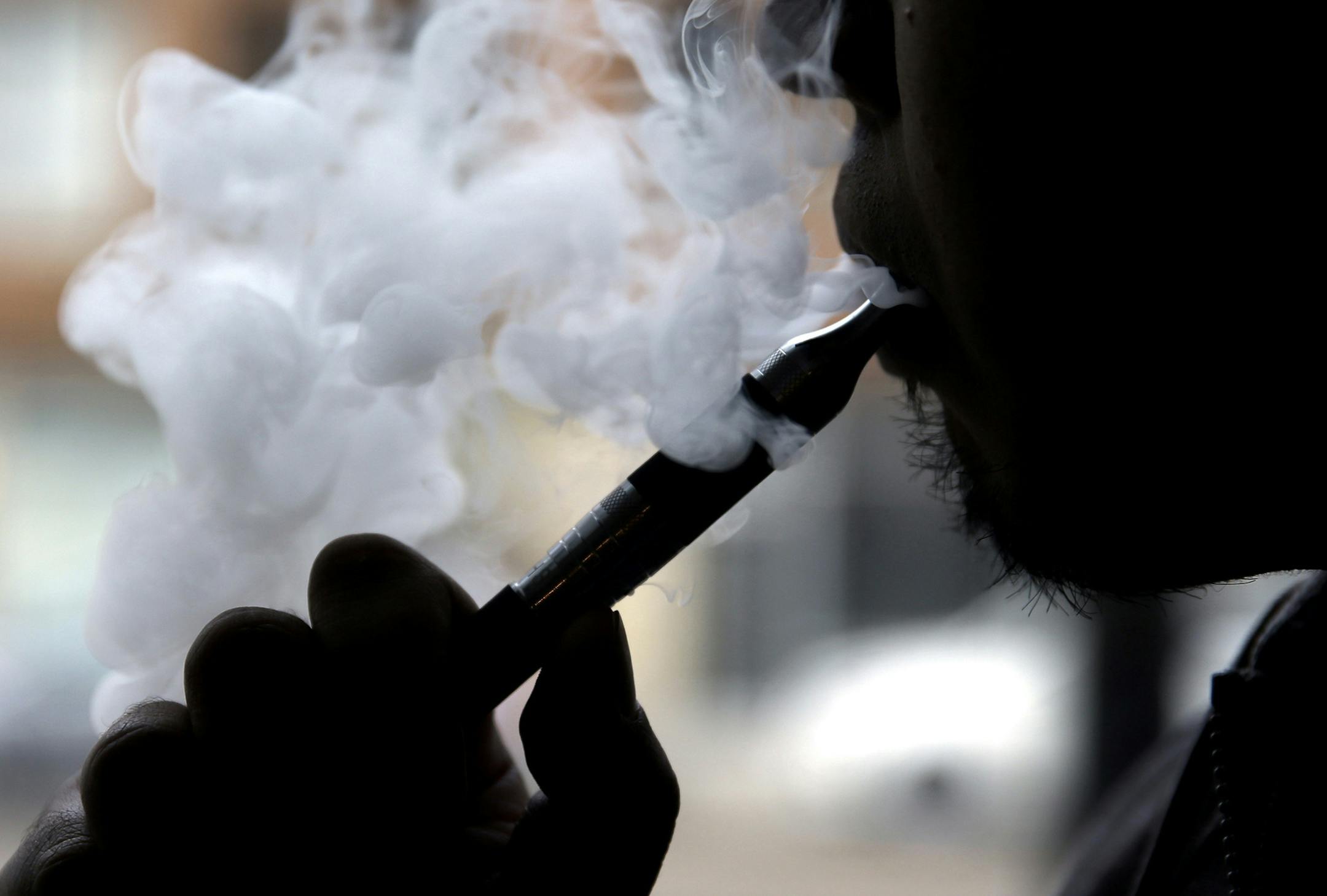 FILE - In this April 23, 2014, file photo, an electronic cigarette is demonstrated in Chicago. The Columbia/Boone County Board of Health has endorsed proposals to ban selling tobacco products to people younger than 21. The Columbia Tribune reports the board also approved on Thursday a proposal to add e-cigarettes to Columbia's restrictions on smoking inside public places. (AP Photo/Nam Y. Huh, File) ORG XMIT: MIN2014120511365831