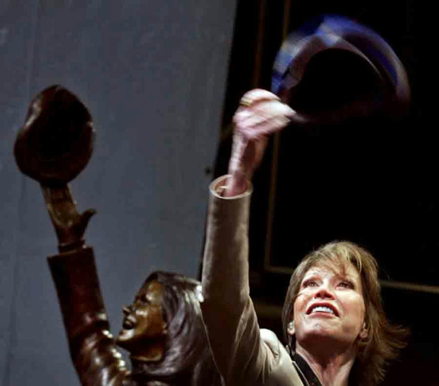 In the May 8, 2002, photo, actress Mary Tyler Moore, standing beside a statue of her in downtown Minneapolis, tossed another tam as the statue was unveiled. Moore died Wednesday.