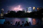 People watched a thunderstorm beyond downtown Minneapolis on Monday night while gathered along the Mississippi River at Boom Island Park to catch a la