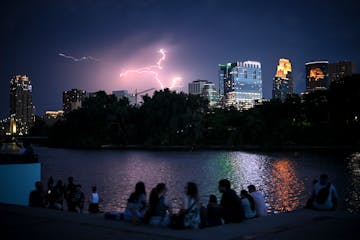 People watched a thunderstorm beyond downtown Minneapolis on Monday night while gathered along the Mississippi River at Boom Island Park to catch a la