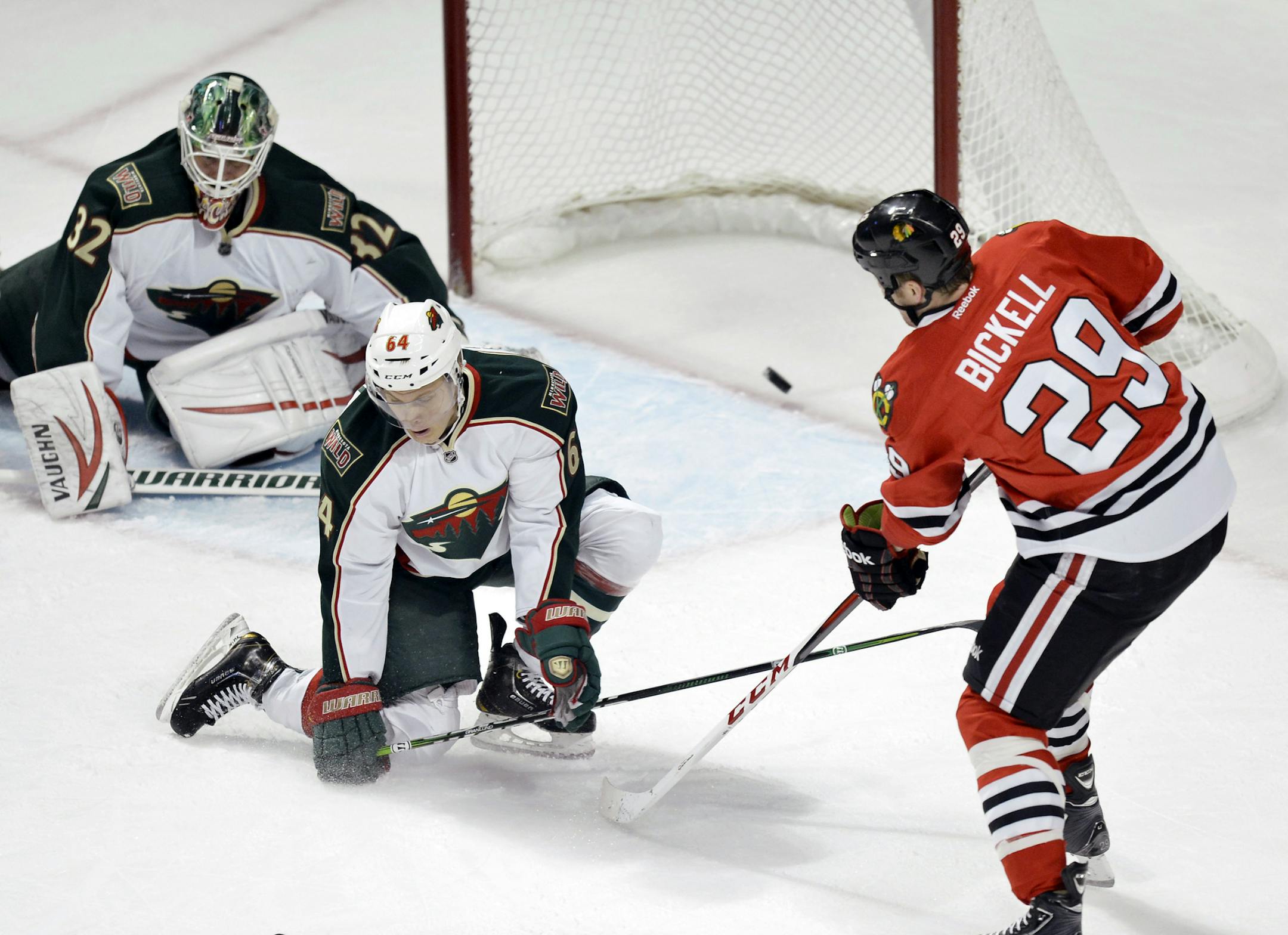 Chicago Blackhawks left wing Bryan Bickell, left to right, scores past Minnesota Wild center Mikael Granlund of Finland, and goalie Niklas Backstrom of Finland during the first period of an NHL hockey game, Tuesday, March 5, 2013 in Chicago. (AP Photo/Brian Kersey)