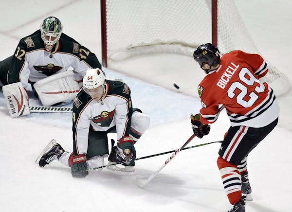 Chicago Blackhawks left wing Bryan Bickell, left to right, scores past Minnesota Wild center Mikael Granlund of Finland, and goalie Niklas Backstrom o