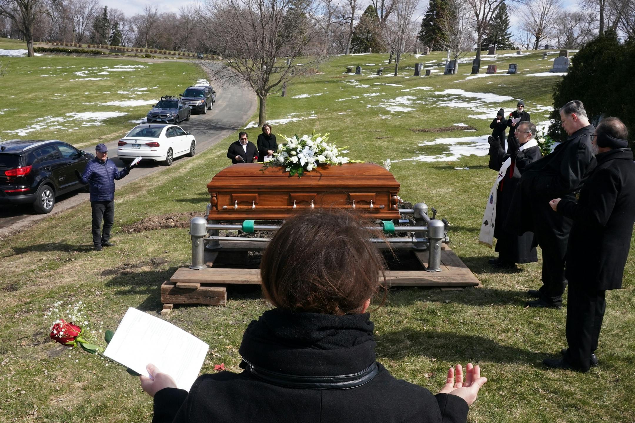 Family and friends including granddaughter Elianne Farhat, center, worked to keep the recommended distancing from one another as they prayed during funeral services for Elie Farhat, who recently died of COVID-19 at the age of 92, at his gravesite Thursday.