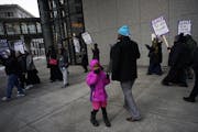 At the Securian Center in downtown St. Paul, several dozen janitors from the SEIU, including Mohamed Geyre with his daughter Fadumo,6, protested their