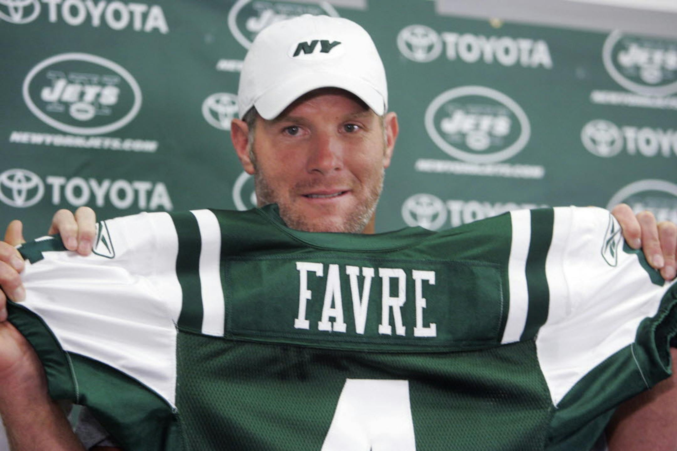 Brett Favre holds up his new New York Jets jersey before an NFL exhibition football game between the New York Jets and Cleveland Browns Thursday