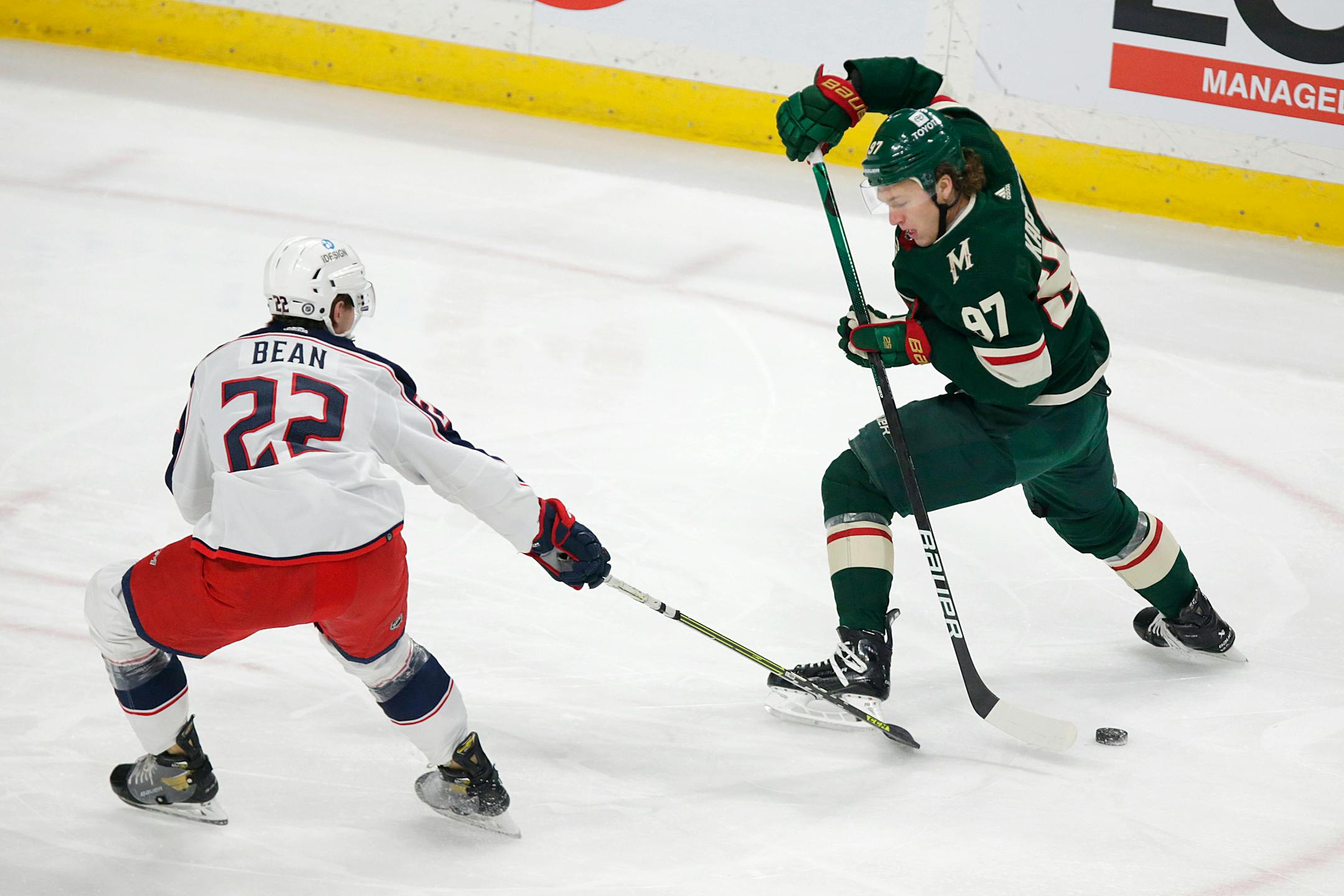 Minnesota Wild left wing Kirill Kaprizov (97) takes the puck between his skates with Columbus Blue Jackets defenseman Jake Bean (22) on defense during the first period of an NHL hockey game Saturday, March 26, 2022, in St. Paul, Minn. (AP Photo/Andy Clayton-King)