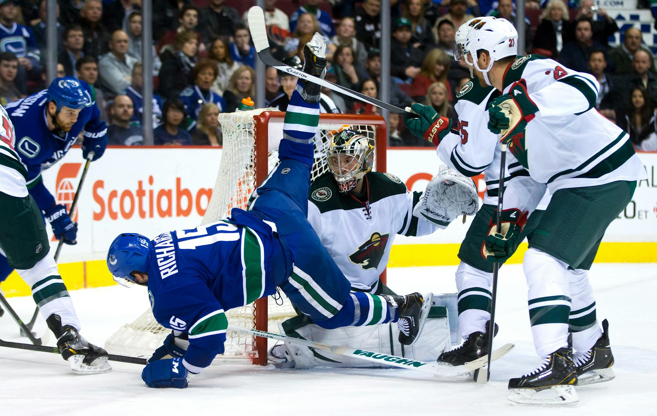 Vancouver Canucks' Brad Richardson, left, is tripped up by Minnesota Wild's Jonas Brodin, back right, of Sweden, in front of Wild goalie Darcy Kuemper as Wild's Kyle Brodziak, right, watches during the first period of an NHL hockey game Friday, Feb. 28, 2014, in Vancouver, British Columbia. (AP Photo/The Canadian Press, Darryl Dyck)