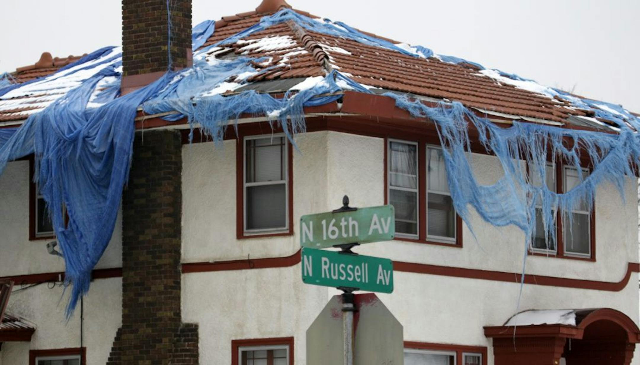 Shredded blue plastic tarps, like this one on the roof of a damaged house at 16th and Russell Avs. N., offer little protection from the elements, frustrating those who want to help.