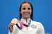 Regan Smith of the United States holds up her bronze medal for the women's 100-meter backstroke at the 2020 Summer Olympics, Tuesday, July 27, 2021, i
