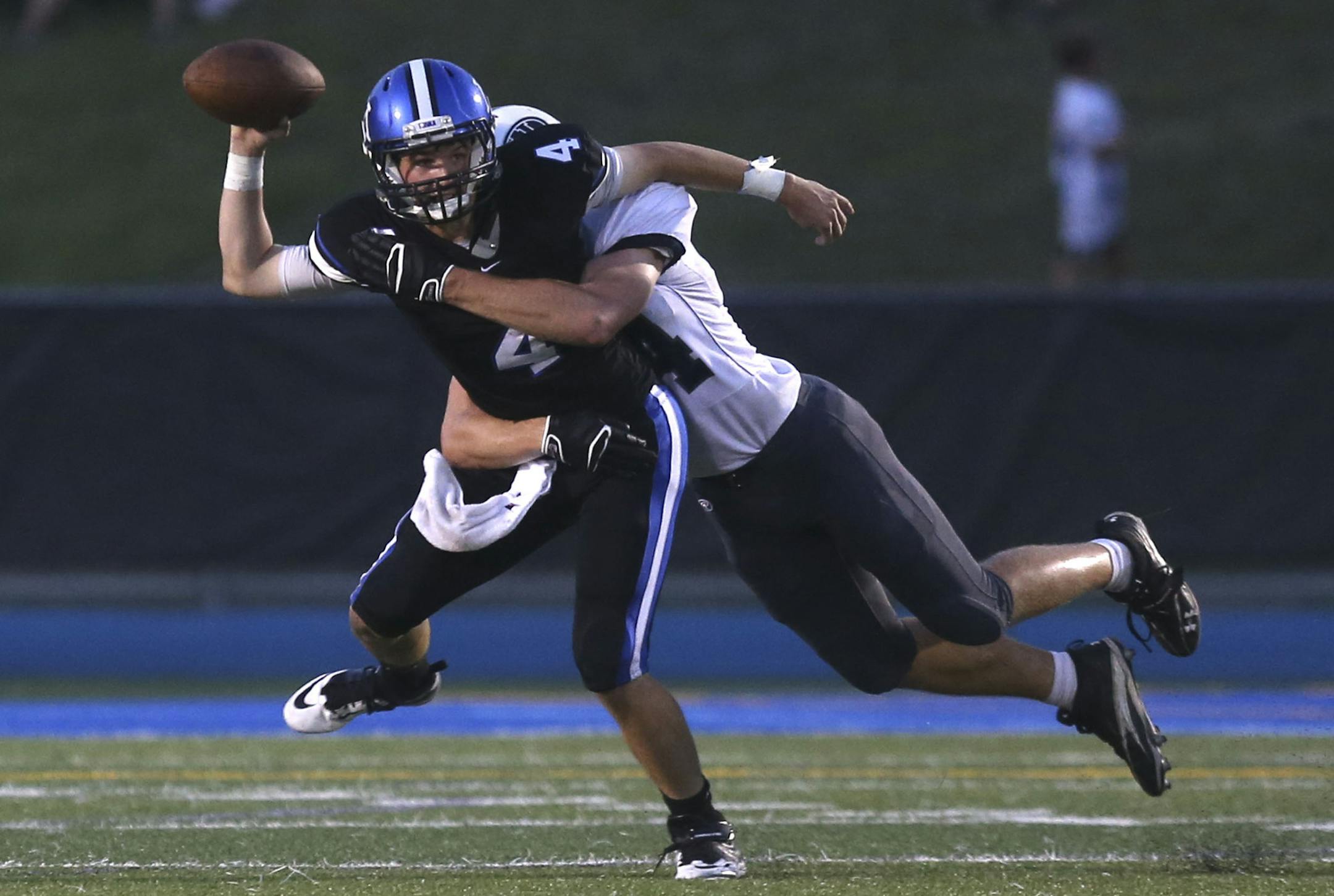 Minnetonka's quarterback Nick Rooney got rid of the ball before Hudson's Ryan Reiter finished the tackle in the second quarter in Minnetonka Min., Friday, August 23, 2013. ] (KYNDELL HARKNESS/STAR TRIBUNE) kyndell.harkness@startribune.com
