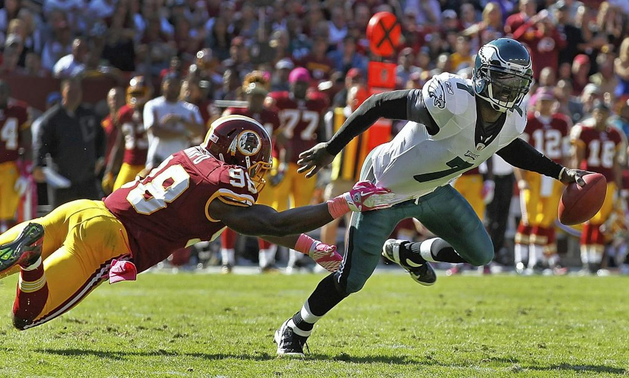 Philadelphia Eagles quarterback Michael Vick, right, scrambles out of the reach of Washington Redskins outside linebacker Brian Orakpo, left, during the first half of an NFL football game in Landover, Md., Sunday, Oct. 16, 2011.