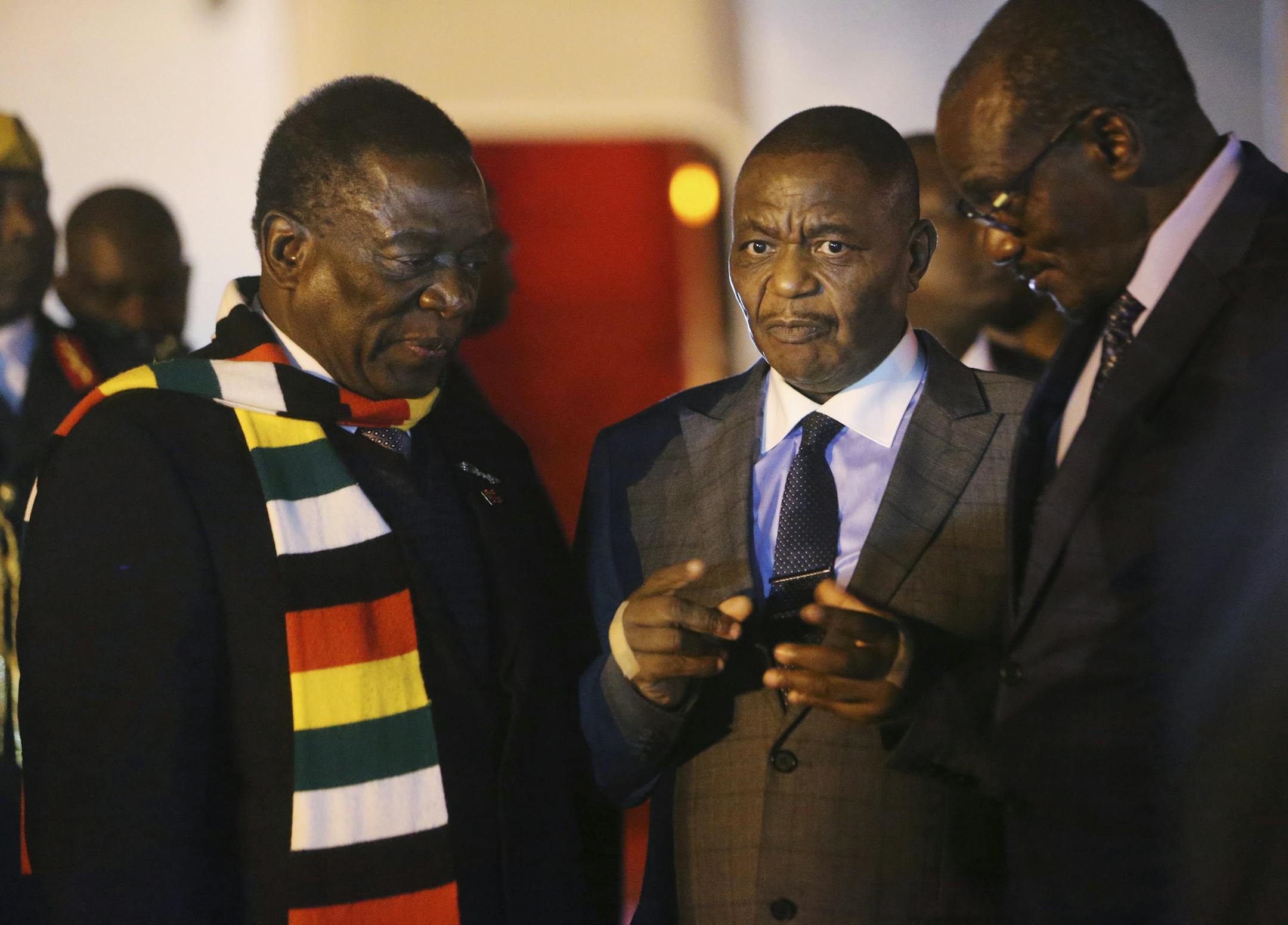 Zimbabwean President Emmerson Mnangagwa, left, arrives at Robert Mugabe International Airport in Harare, Zimbabwe, Monday, Jan. 21, 2019. Mnangagwa arrived in Harare late Monday after cutting short his fund-raising trip in order to address the country's economic crisis and crackdown. (AP Photo/Tsvangirayi Mukwazhi)
