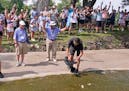A cameraman films and the gallery cheers as Emiliano Grillo's ball comes to a rest against a rock after floating down a concrete drainage canal on the