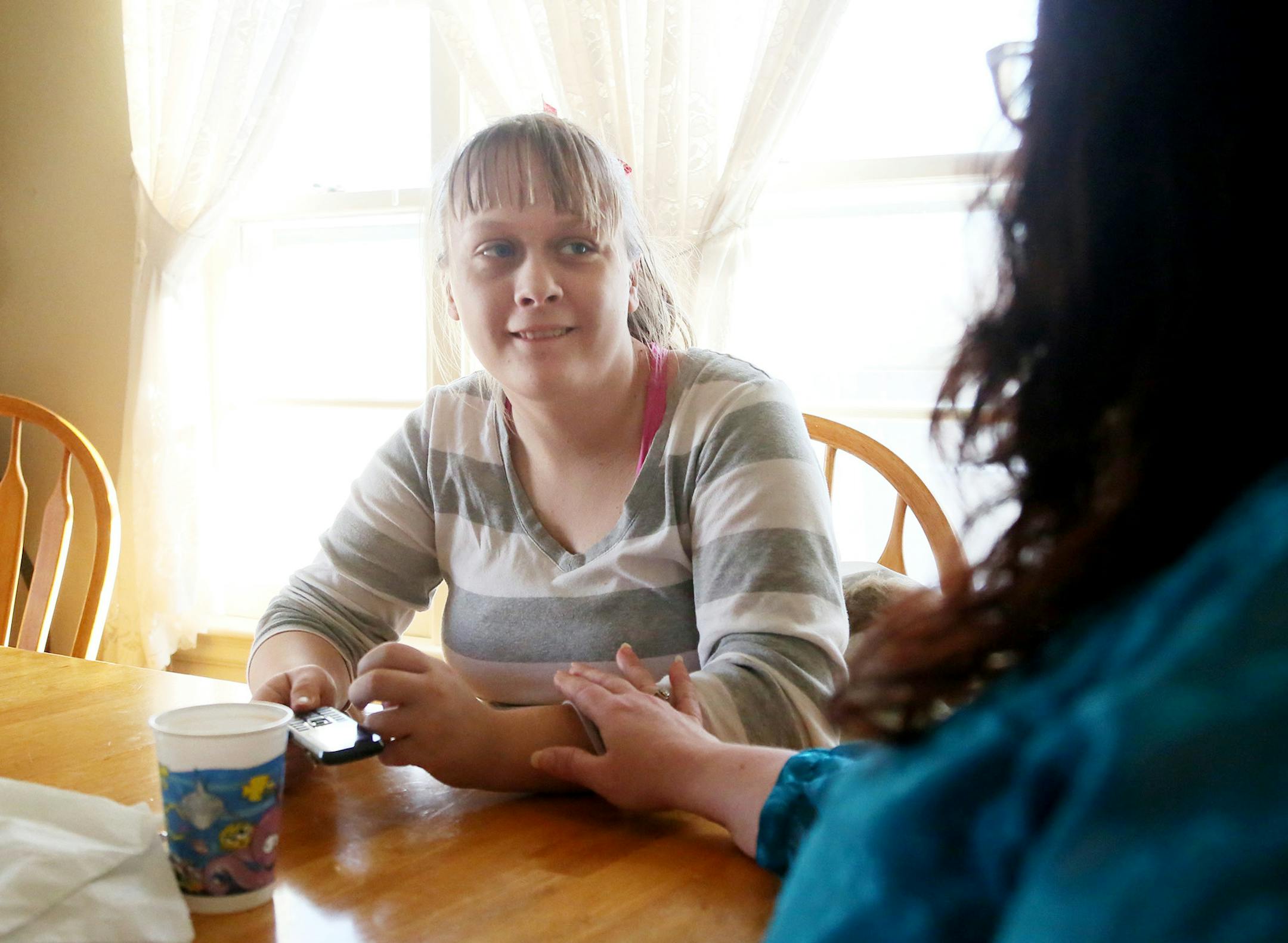 Here, Candy Hoover gently touches Brianna, 18, at home Thursday, Feb. 12, 2015, in Cambridge, MN. Brianna and her brother, Cory, who are twins and both have fetal alcohol syndrome, have lived with foster mom Candy Hoover since they were young. They have severe mental impairments, and need help with their homework and even basic tasks, such as buttoning their shirts. However, Brianna is unable to live more independently because she has been on a waiting list for basic social services for the past
