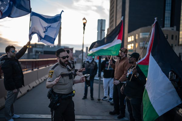 A member of the Ramsey County Sheriff's Department made sure that supporters of Israel, left, and Palestinian supporters were peaceful during a rally 