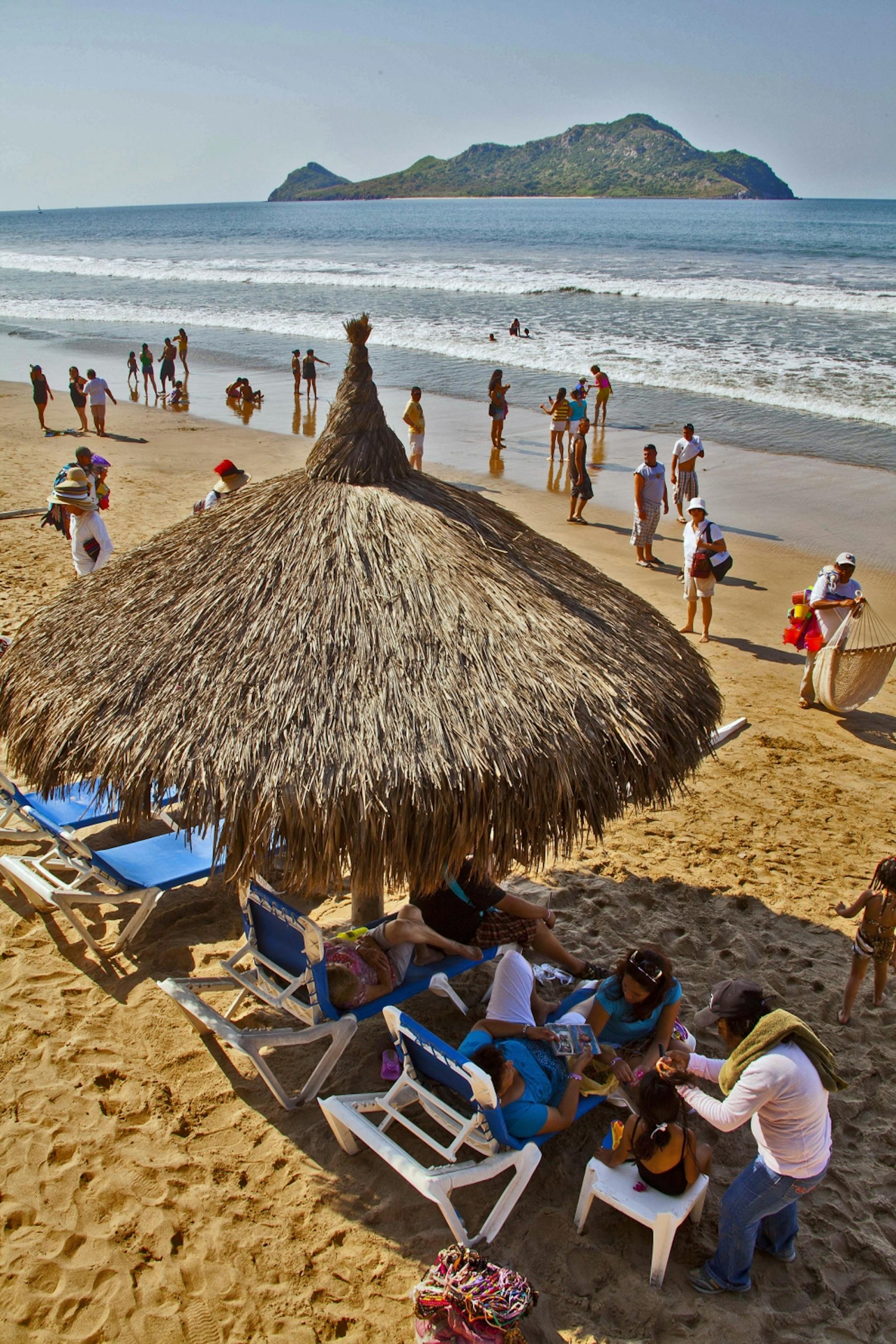 Vacationers relax under a palapa in front of the family-friendly El Cid Castilla Hotel in Mazatlan, Mexico.