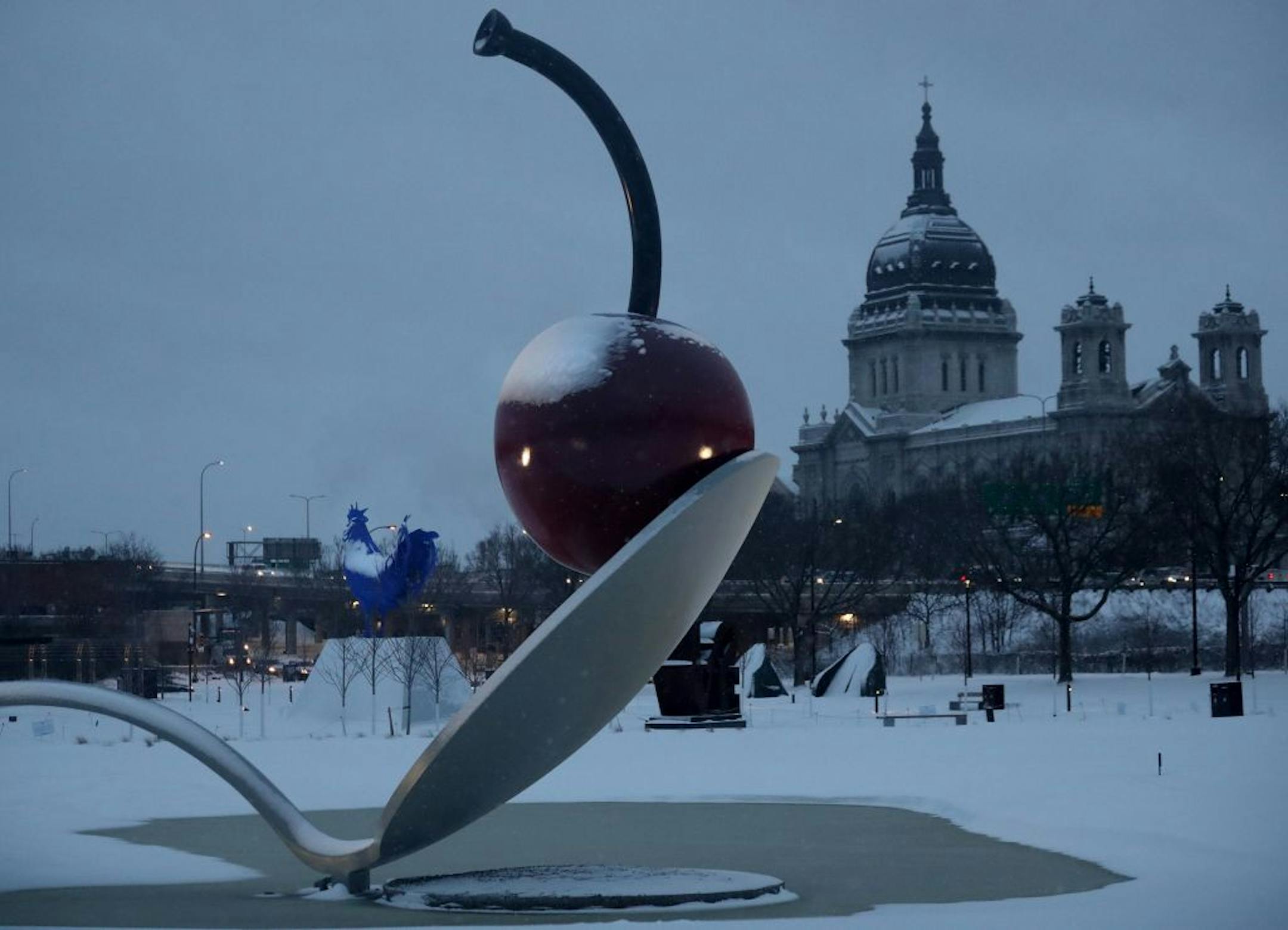 The Walker Art Center's Spoon Bridge and Cherry, designed by husband and wife Claes Oldenburg and Coosje van Bruggen, and Katharina Fritsch's gigantic blue rooster are coated in in the Sculpture Garden are coated in fresh snowfall Tuesday, March 6, 2018, in Minneapolis, MN.