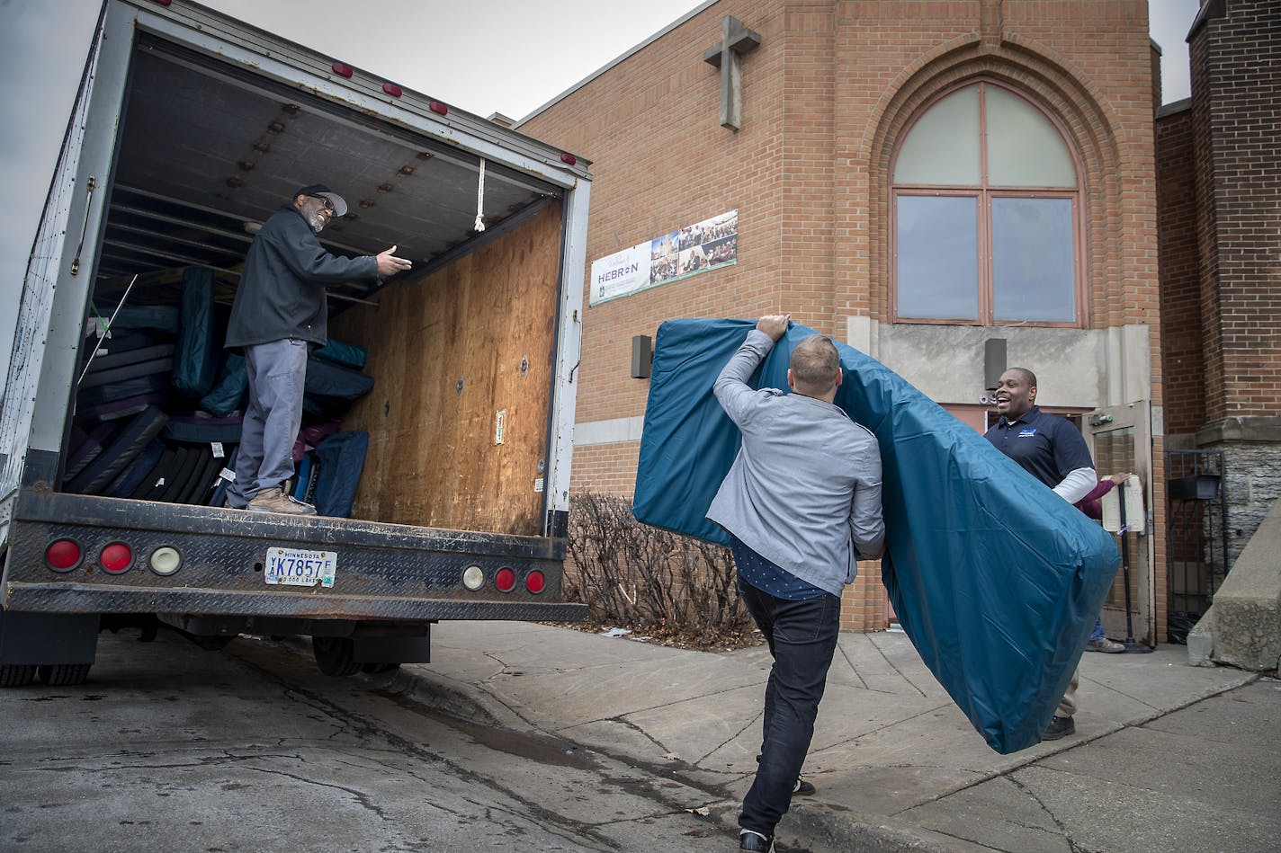 Derwin Turner, left, unloaded dozens of foam mats, along with Elim Church Lead Pastor Paul Stephen Olson, center, and KMS owner Ken McCraley, right, into Strong Tower Parish and Elim Church in northeast Minneapolis, Monday, February 3, 2020. Elim Church received $250,000 from a new state fund and will shelter up to 40 men and women as early as this week.