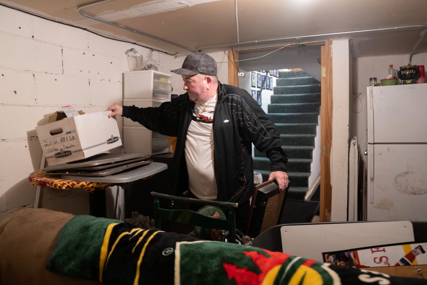 Dennis Manning packs up memorabilia from his shop's walls in the basement Tuesday, Nov. 07, 2023, at Sportsmen's Barbers in Columbia Heights, Minn. ]