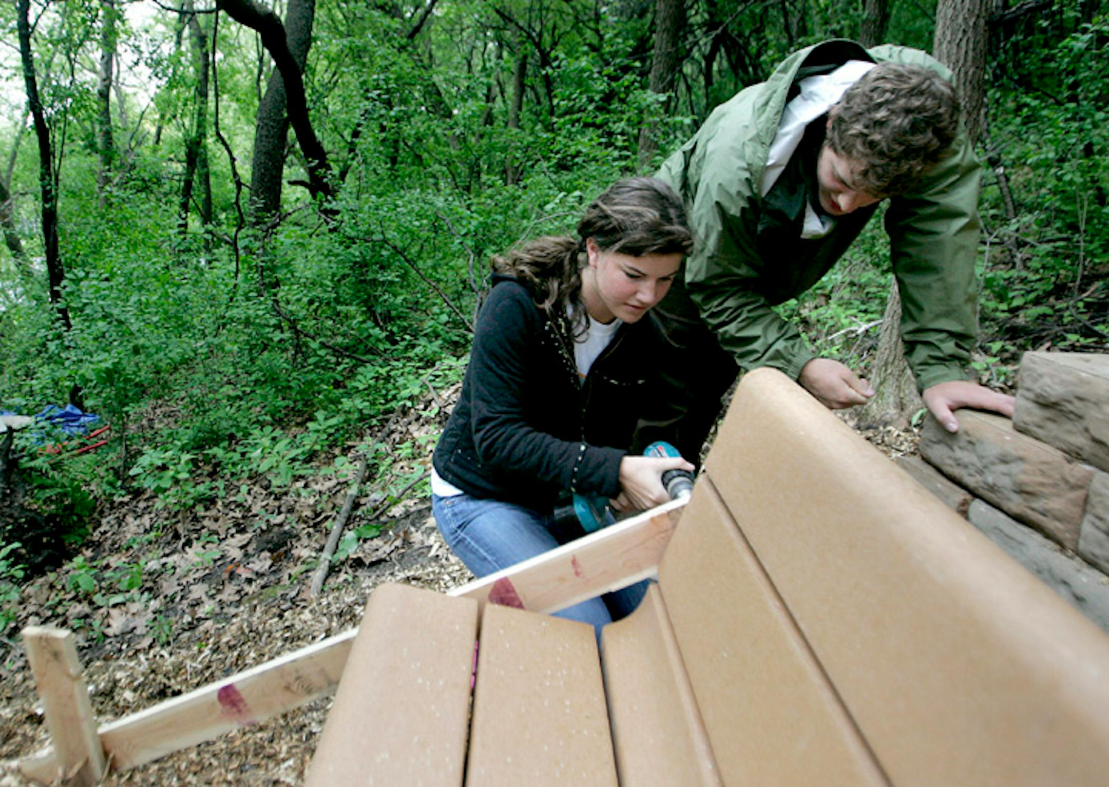 Seniors Caroline Goan, left, and True Overholt put the finishing touches on benches at an outdoor classroom they helped plan and build during their final semester at Edina High School.