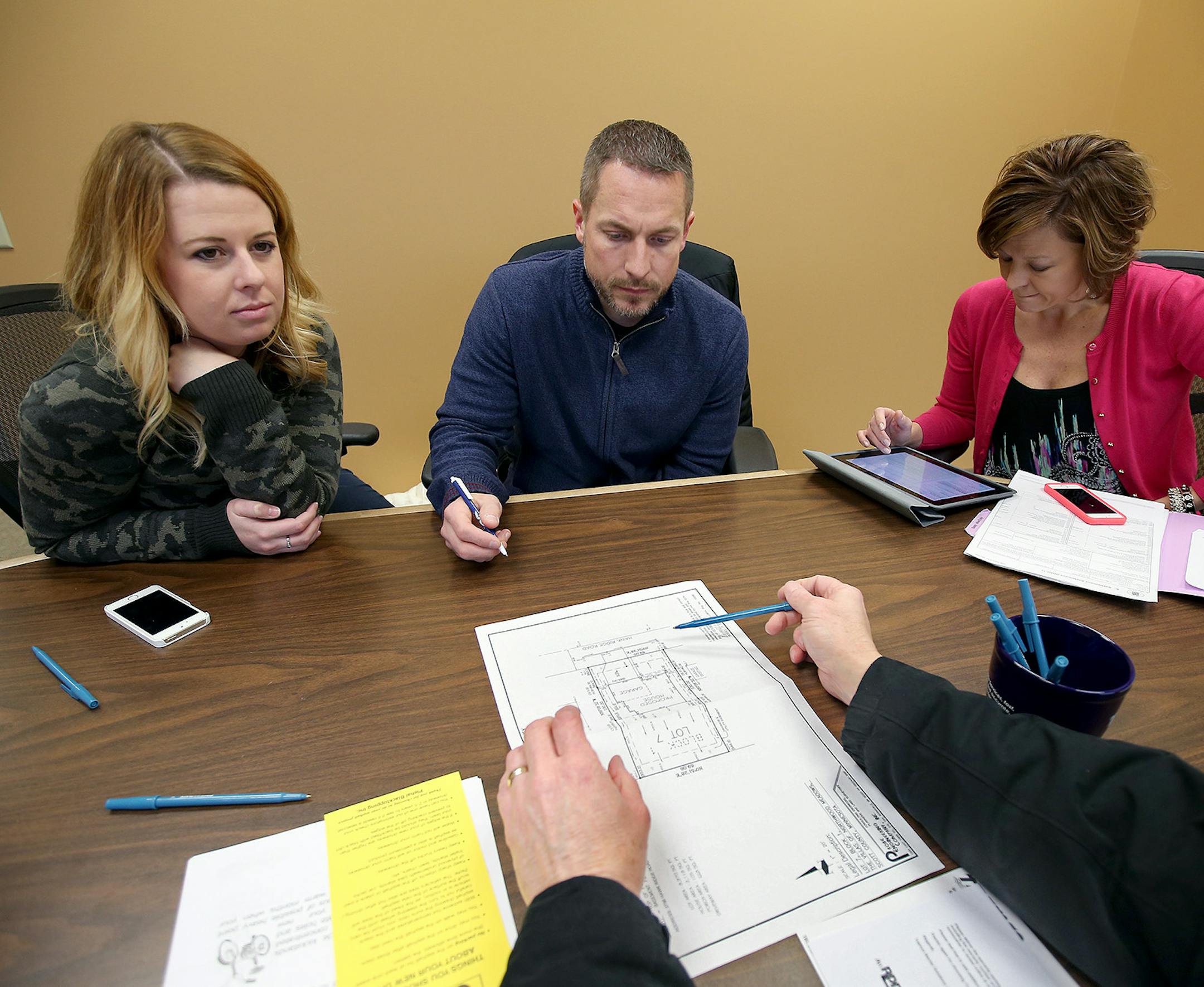 Emily and Mike Slates, left, went through the process of closing on their newly built home with sales agent, Amy Jurek, right, of ReMax Advantage Plus, at Trademark Title, Friday, December 5, 2014 in Bloomington, MN. ] (ELIZABETH FLORES/STAR TRIBUNE) ELIZABETH FLORES • eflores@startribune.com