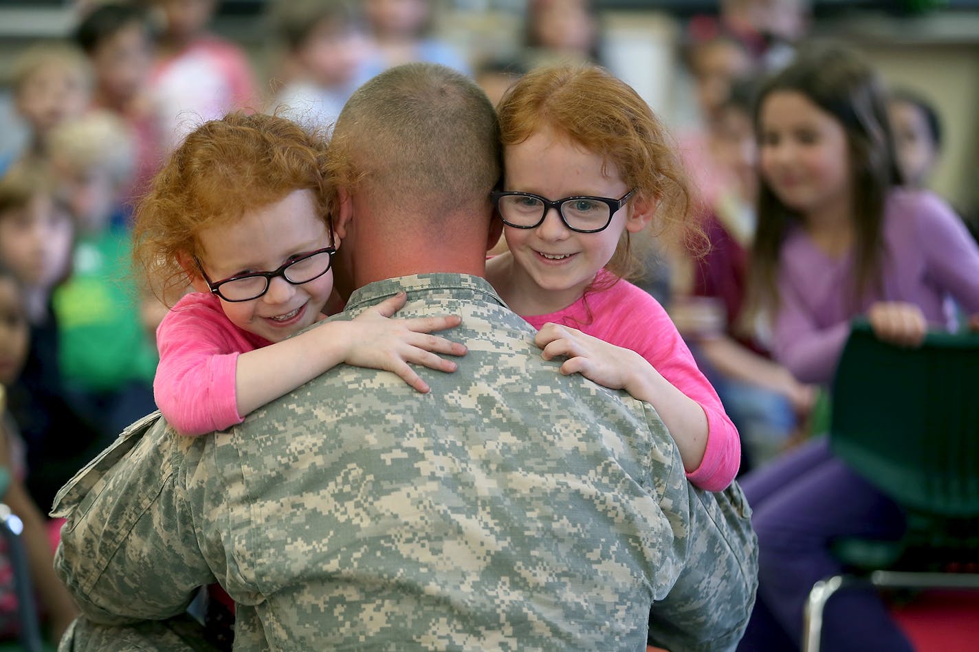 Hale Elementary School kindergarten twins Kaylee, left, and Ariana Martinez received a big hug from their father Jacob Martinez after surprising them in class, Monday, April 27, 2015 in Minneapolis, MN. Martinez returned after a year in Kuwait and Iraq.