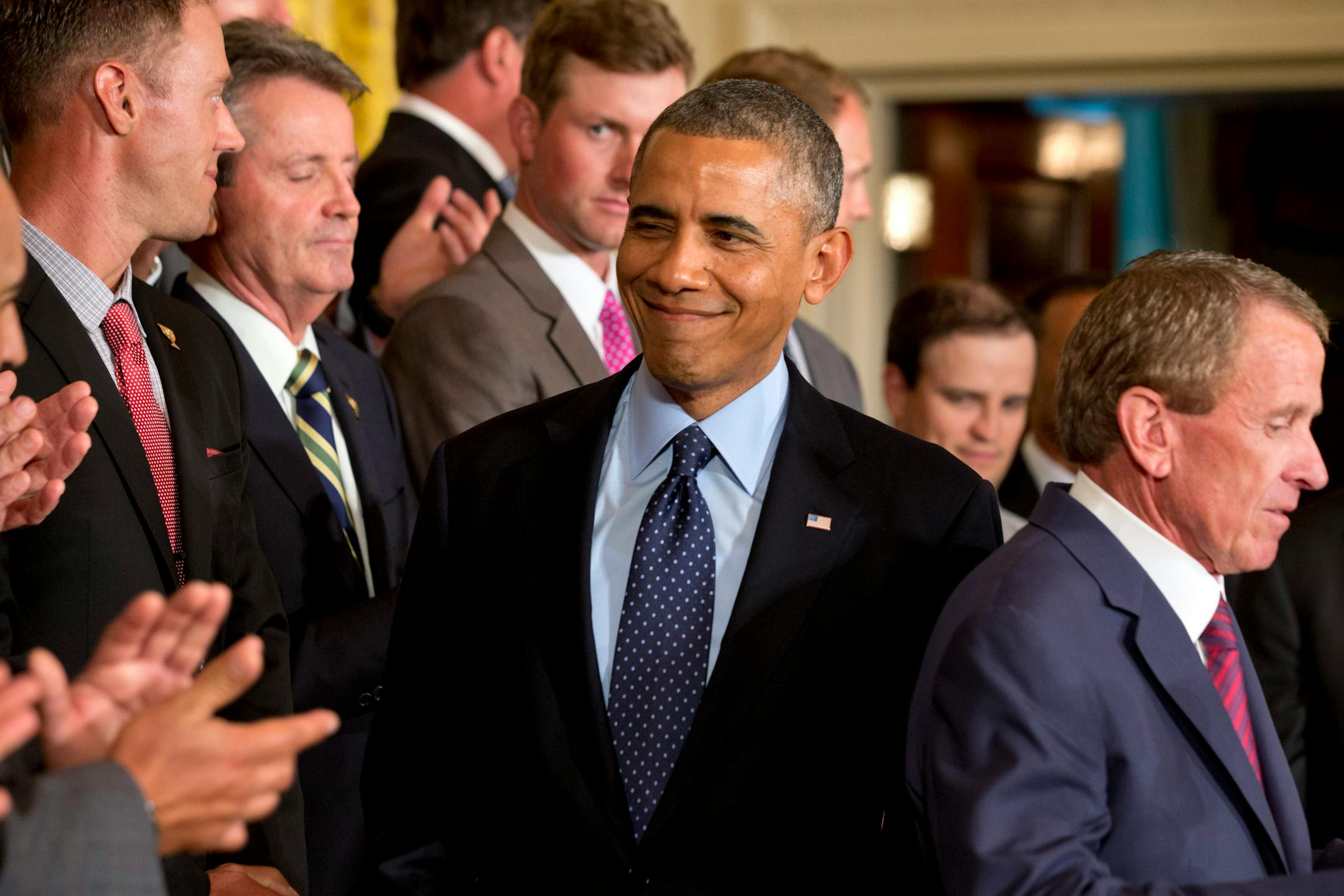 President Barack Obama winks as he is applauded on arrival at a ceremony honoring the 2013 Presidents Cup U.S. team during a ceremony in the East Room of the White House, Tuesday.